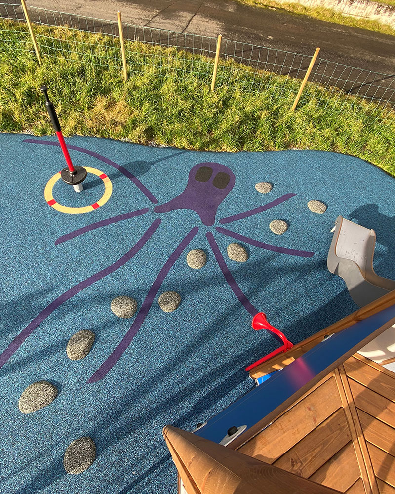 Ariel shot of a large playground, with wet pour surfacing showing color, excitement and clear pathways around the playground.